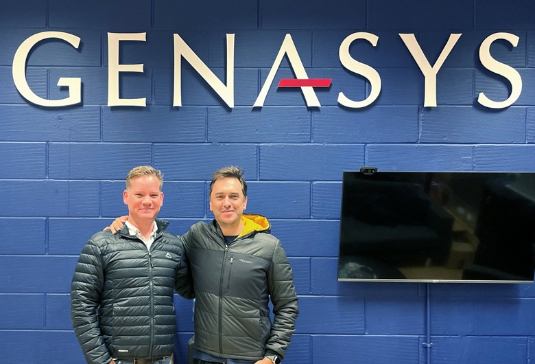 Genasys's two CEOs standing in front of the Genasys sign in the office