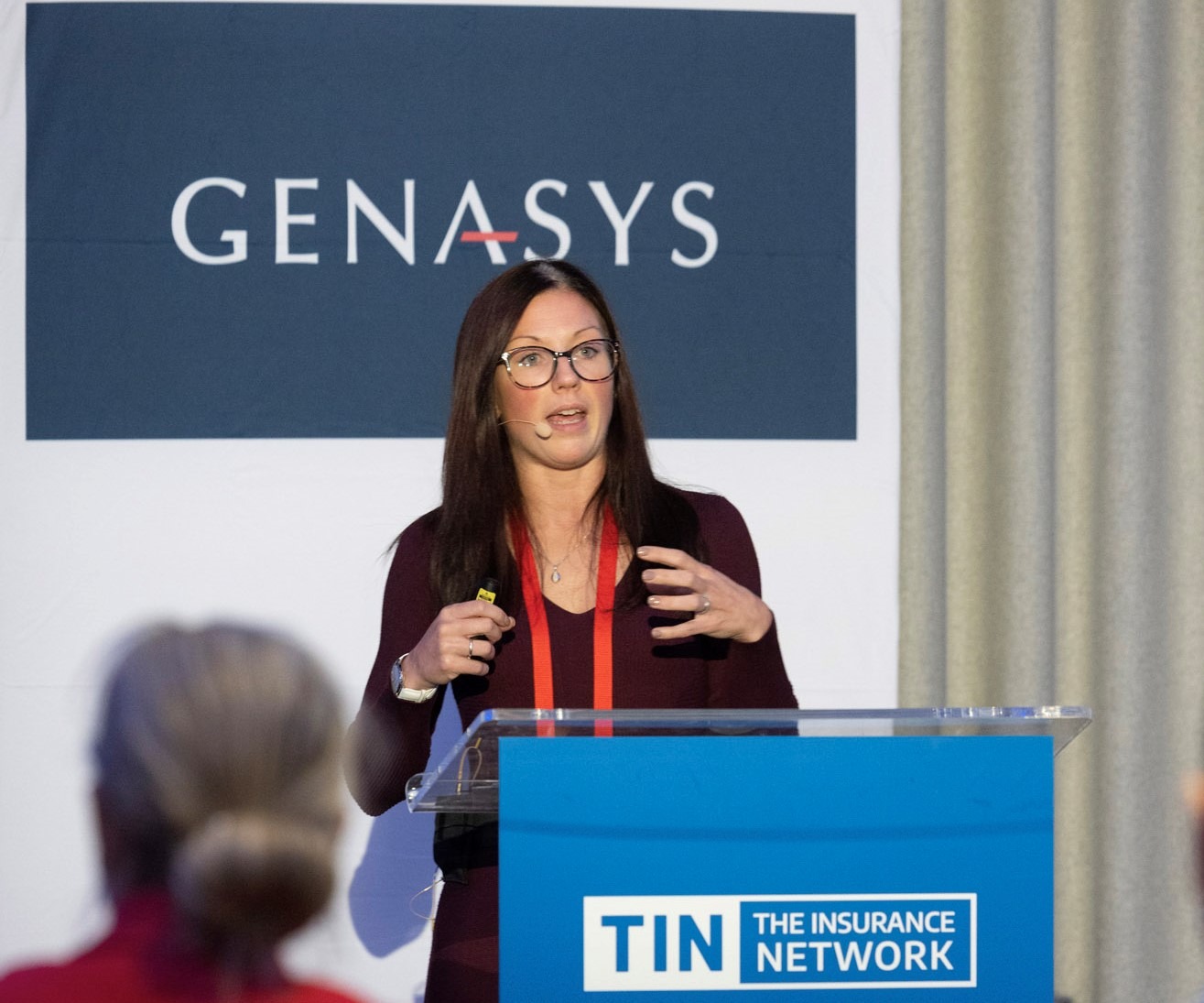 Jen Dallas, Digital Director at RSA Insurance, presenting at TINtech in front of a Genasys banner