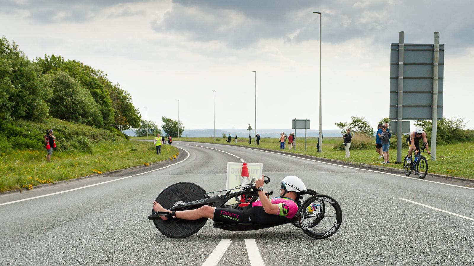 Close-up of James Bilham cranking his handcycle mid-race, race number 358 on his helmet