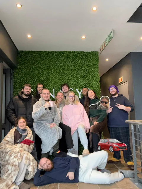 Twelve colleagues in pyjamas and dressing gowns in front of the Genasys wall