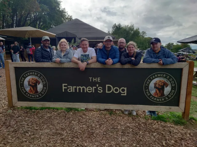 Seven colleagues leaning over a sign at The Farmer\'s Dog