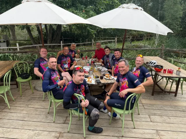 Eight colleagues in Genasys cycling kit around a table on a cafe terrace